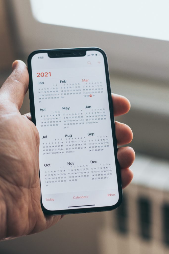 Une personne tient son smartphone avec un calendrier digital dessus.